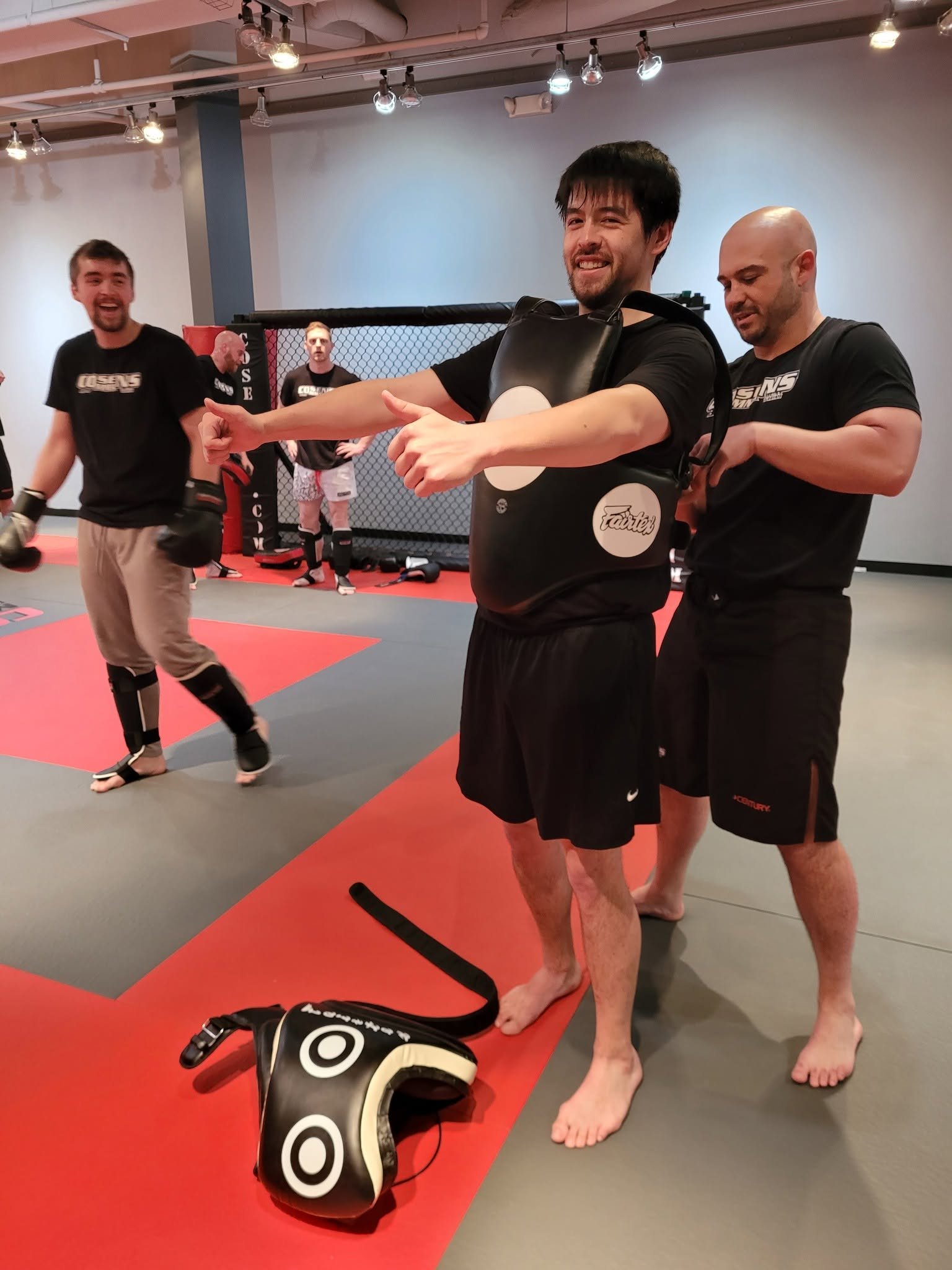 Coach helping a smiling adult beginner during MMA training