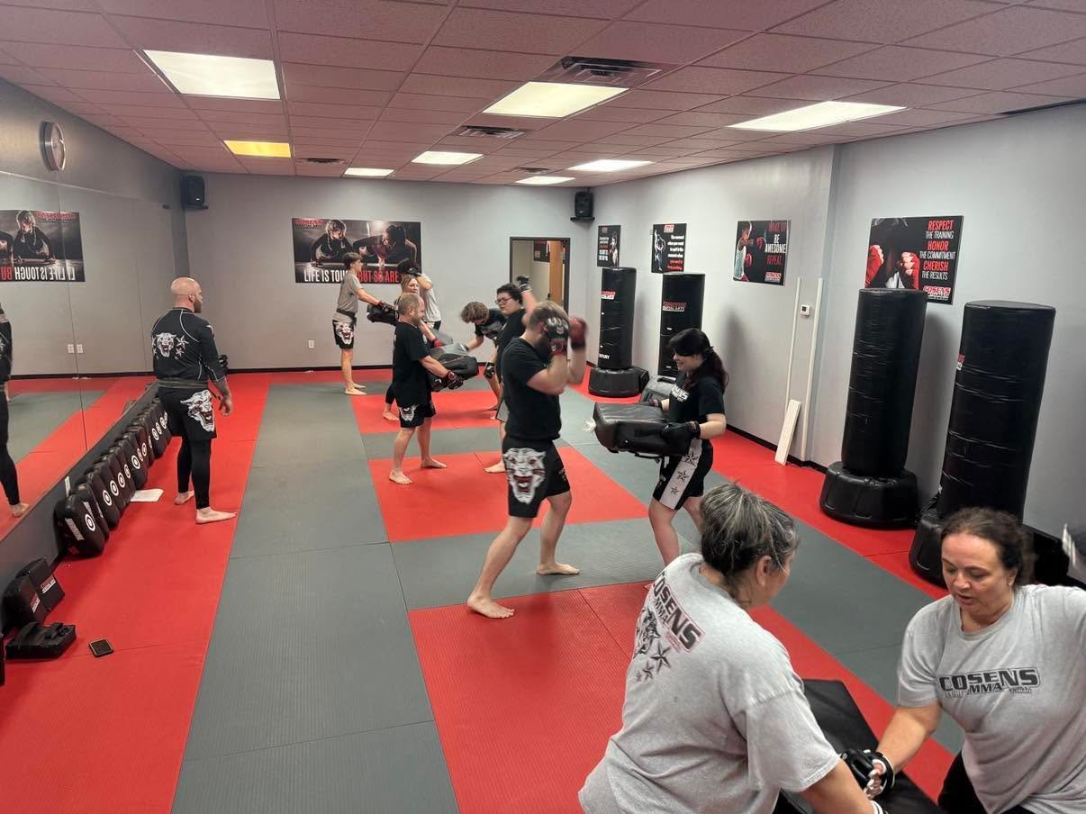 Men and women practicing controlled padwork in adult MMA class