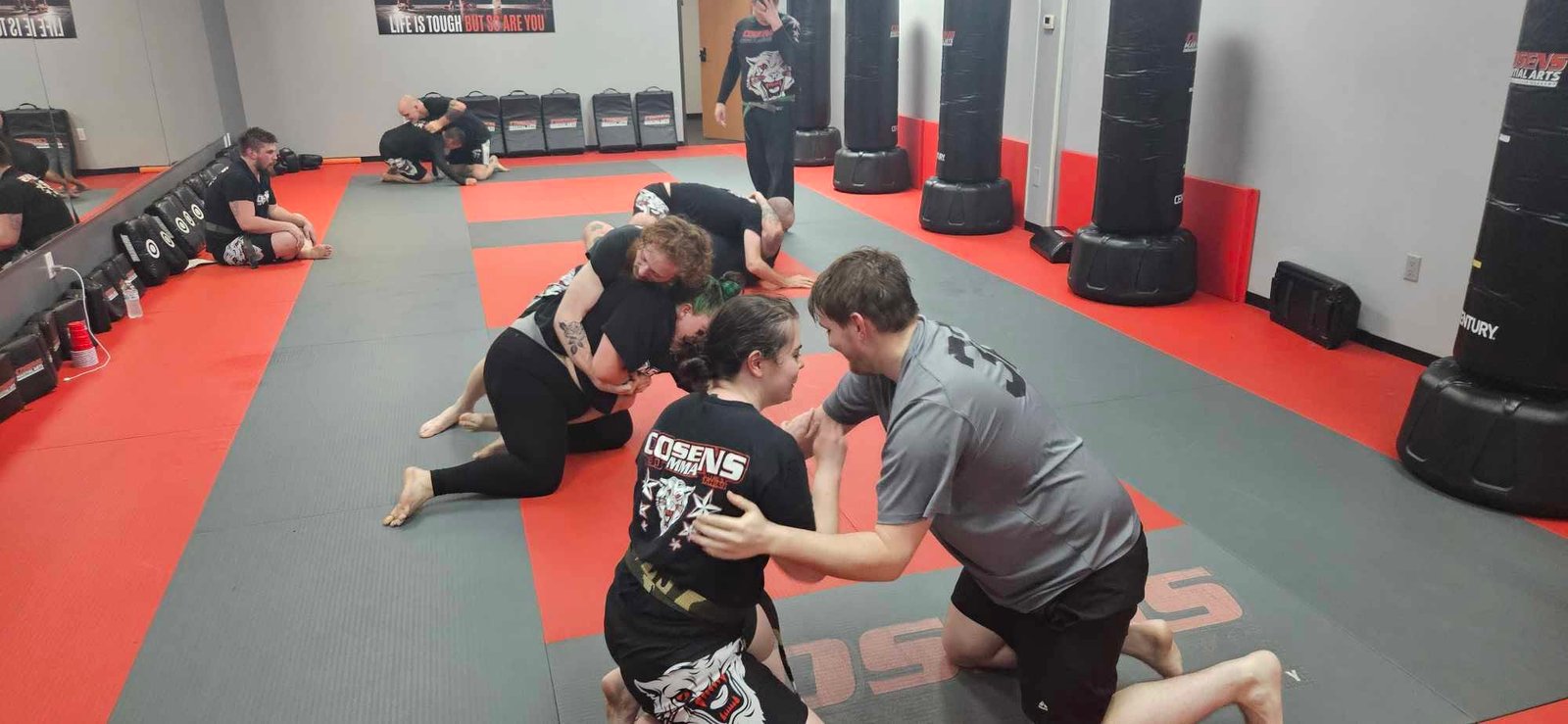 Adult students learning grappling together in a controlled class